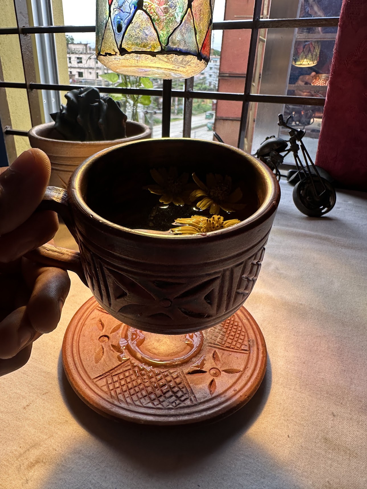 Artisan terracotta cup held in hand under sunbeam